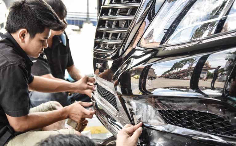 Techniciens posant un film de protection PPF sur la calandre d’une voiture