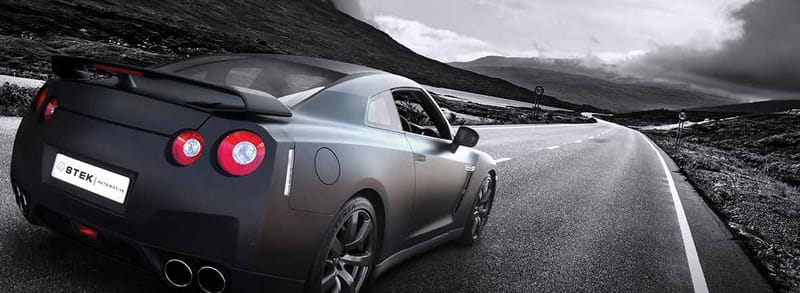 Coupé sportif noir mat sur route de montagne